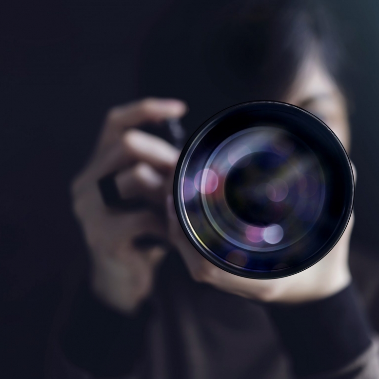 Photographer Taking Self-Portrait. Woman using Camera to Taking Photo. Dark Tone, Front View. Selective focus on Lense. Straight into a Camera